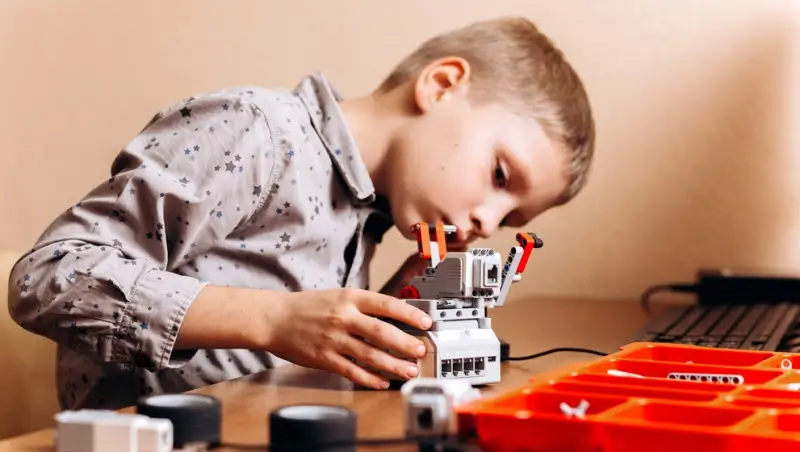 Child learning programming concepts using coding toys and a programmable robot