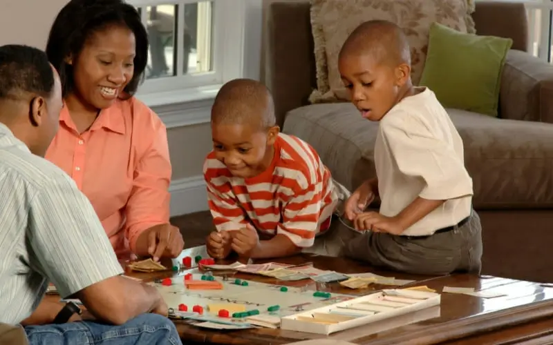 Family playing board games for kids together, laughing and enjoying quality time at home